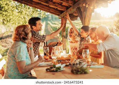 Happy family enjoying meal together in vineyard - Powered by Shutterstock