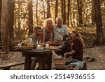 Happy family enjoying picnic in the woods while eating grapes and laughing on a beautiful sunny day