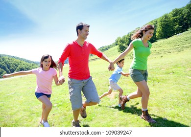 Happy Family Enjoying And Running Together In The Mountains