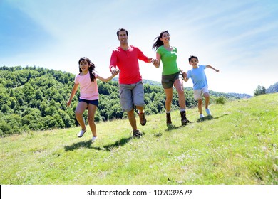 Happy Family Enjoying And Running Together In The Mountains