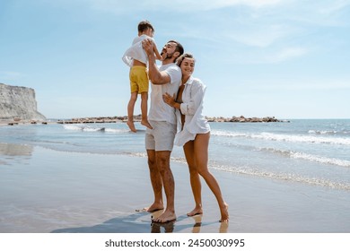 Happy family enjoys a playful walk along the sea on a Mediterranean beach. - Powered by Shutterstock