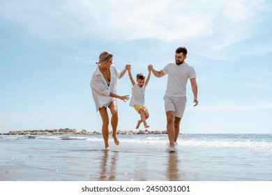 Happy family enjoys a playful walk along the sea on a Mediterranean beach. - Powered by Shutterstock