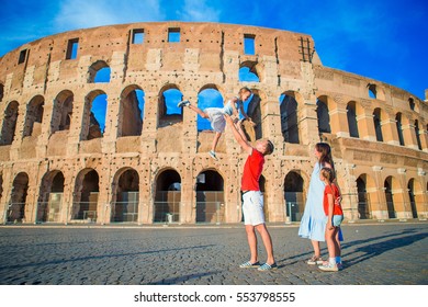 Happy Family In Europe. Parents And Kids In Rome Over Coliseum Background. Italian European Vacation Together