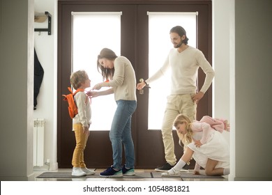 Happy Family Everyday Preparations, Caring Parents Getting Kids With Backpacks Ready For First Day At School Standing At House Hall Together, Boy Son And Girl Daughter Dressing In The Morning At Home