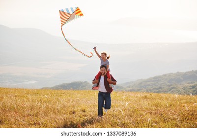 Happy Family Father And Child Daughter Launch A Kite On Meadow
