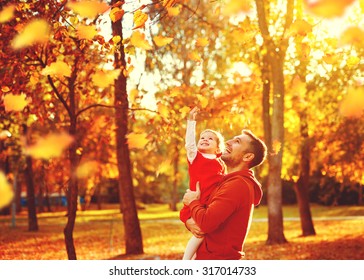 Happy Family Father And Child Daughter On A Walk In The Autumn Leaf Fall In Park