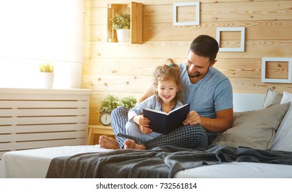 Happy Family Father And Child Daughter Reading Book In Bed
