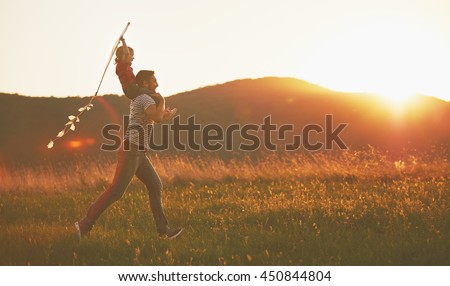 happy family father and child run on meadow with a kite in the summer on the nature