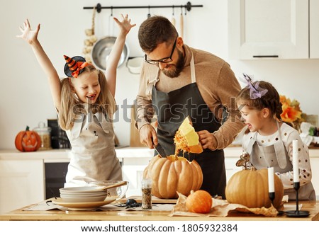 happy family   father  and children daughters prepare for Halloween by carving pumpkins at home in the kitchen
