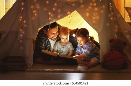 happy family father and children reading a book with a flashlight in a tent at home
 - Powered by Shutterstock