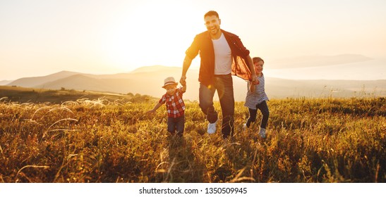 Happy Family Father And Children Running In Nature At Sunset
