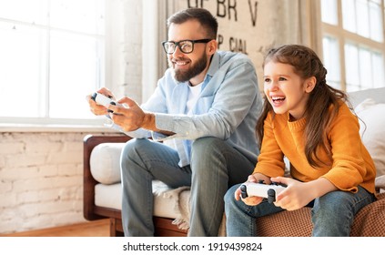 happy family father and daughter laugh and play video games together using a video game console - Powered by Shutterstock