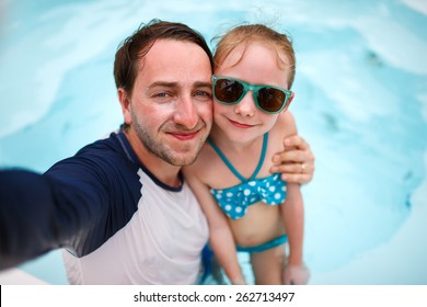 Happy family father and his adorable little daughter at outdoors swimming pool making selfie - Powered by Shutterstock