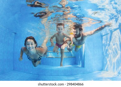 Happy Family - Father And Mother With Baby Boy Swimming And Diving Underwater With Fun In Blue Pool. Healthy Lifestyle, Active Parents, And People Water Sports Activity On Summer Vacation With Child