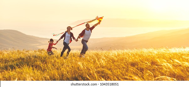 Happy family father,  mother and child daughter launch a kite on nature at sunset