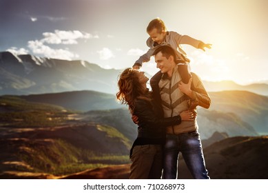 Happy Family Of Father Mother And Little Son Having Fun In Sunset Mountains