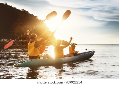 Happy family of father mother and son kayaking and having fun at sunset sea bay