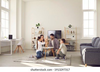 Happy family father mother and two children sitting on floor and playing at home together during weekend. Family spending happy time at home and having fun with children concept