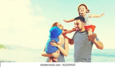 Happy Family Of Father, Mother And Two Children, Baby Son And Daughter On  The Beach At Sunset