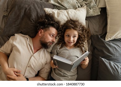 Happy Family. Father Puts His Daughter To Bed. Reading Before Bed. Time For A Magical Story. Spend Time Together. Dad And Daughter At Home