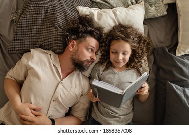 Happy Family. Father Puts His Daughter To Bed. Reading Before Bed. Time For A Magical Story. Spend Time Together. Dad And Daughter At Home