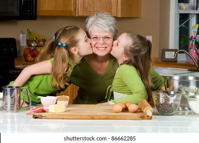 Happy Family Featuring A Friendly Grandma Baking Cookies In A Home Kitchen With Her Two Grandchildren.