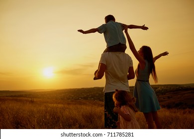 Happy Family In The Field At Sunset.