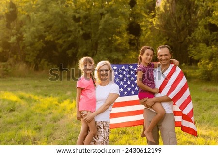 Happy family in field with USA, american flag on back.