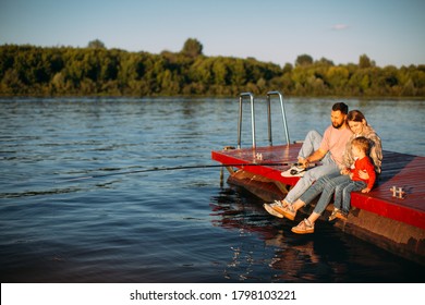 Happy Family Fishing On The Pier On The River Or Lake In Summertime. Photography For Ad Or Blog About Family And Travel