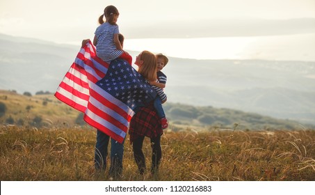 happy family with the flag of america USA at sunset outdoors