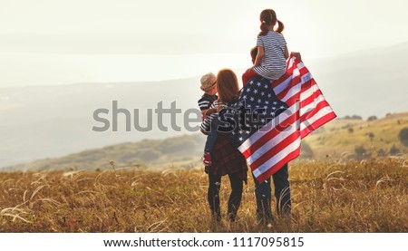 happy family with the flag of america USA at sunset outdoors
