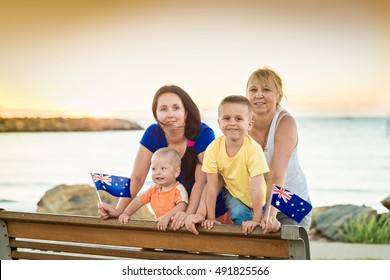 Happy Family With Flags Of Australia On The Beach At Sunset On Australia Day