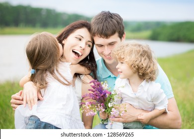 Happy Family With Flowers Having Fun Outdoors In Spring Field