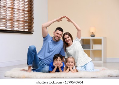 Happy Family Forming House Roof With Their Hands At Home. Insurance Concept