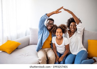 Happy family forming house roof with their hands at home. Insurance concept. Concept of housing and relocation. happy family mother father and kids with roof at home - Shutterstock ID 1993257401