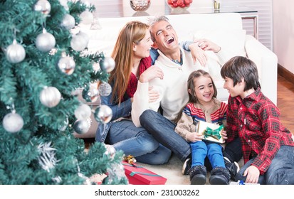 Happy Family Of Four Celebrating Chrismas Near Tree At Home. Family Concept.