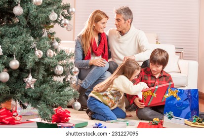 Happy Family Of Four Celebrating Chrismas Near Tree At Home. Family Concept.