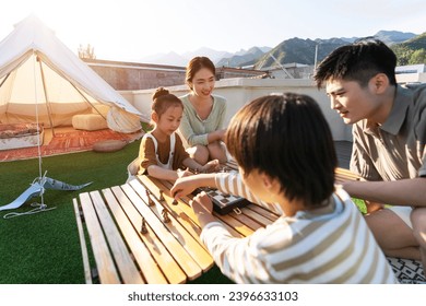 The happy family of four in outdoor play chess - Powered by Shutterstock