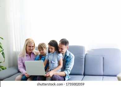 Happy Family Of Four Parents And Cute Little Kids Children Enjoy Using The Tablet, Watching Cartoons, Make Internet Video Call Or Shopping Online Looking At Computer Screen Sit Together At Home