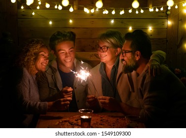 Happy Family Of Four People Sparkling Wishing A Wonderful New Year 2020. Large Pizza On The Wooden Table. Multi Generation. Concept Of Happiness And Love In A Dark Night