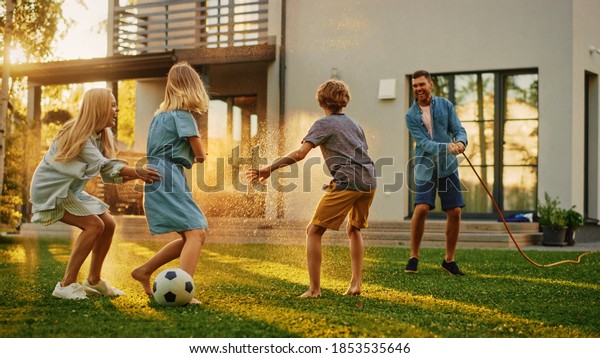 Happy Family of Four Playing with Garden Water Hose,\
Spraying Each Other. Mother, Father, Daughter and Son Have Fun\
Playing Games in the Backyard Lawn of Idyllic Suburban House on\
Sunny Summer Day