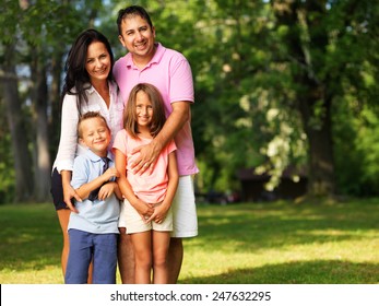 Happy Family Of Four Posing Outside