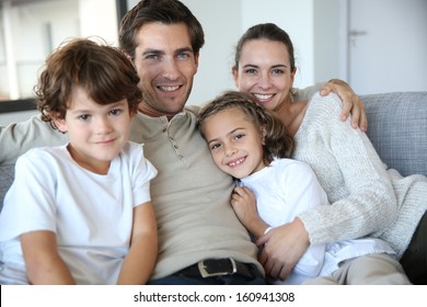 Happy Family Of Four Relaxing In Sofa