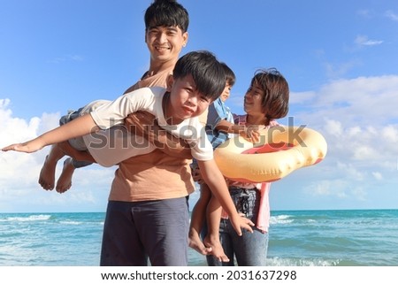 Happy family of four spend time together on tropical sand beach, father playing with kid, daddy carrying cute son, lifting his boy up, joyful parents and children on summer holiday vacation.