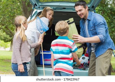 Happy Family Of Four Unloading Car Trunk While On Picnic