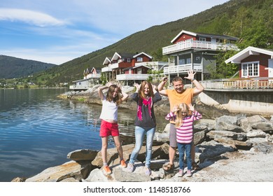 Happy Family -  Fun Smiling Parents And Their Two Daughters  Near The Traditional Red Norwegian House, Norway
