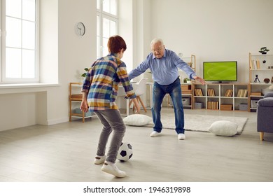 Happy family generation bonding, sport game and fun during coronavirus quarantine. Elderly grandfather playing football with preteen grandson in home living room enjoy spending time together - Powered by Shutterstock