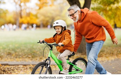 Happy family grandfather teaches boy grandson  to ride a bike in autumn park   in nature - Powered by Shutterstock