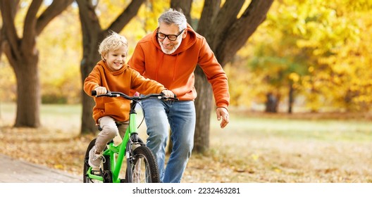 Happy family grandfather teaches boy grandson  to ride a bike in autumn park   in nature - Powered by Shutterstock