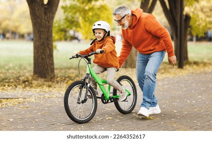 Happy family grandfather teaches boy grandson  to ride a bike in autumn park   in nature - Powered by Shutterstock